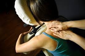 Hands working on a seated client's shoulders