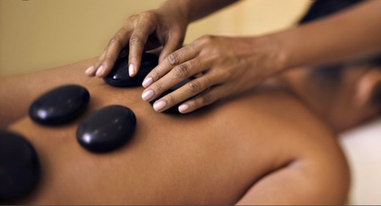Smooth hot stones and hands resting on a client's back